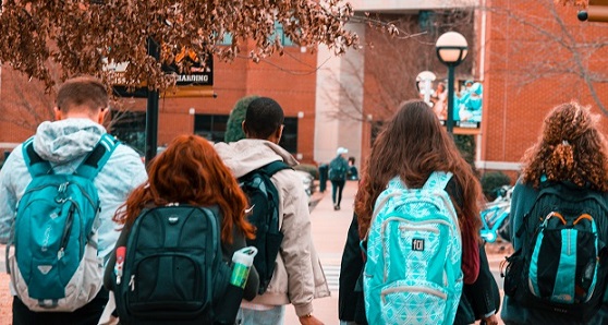 Students wearing backpacks walking towards building